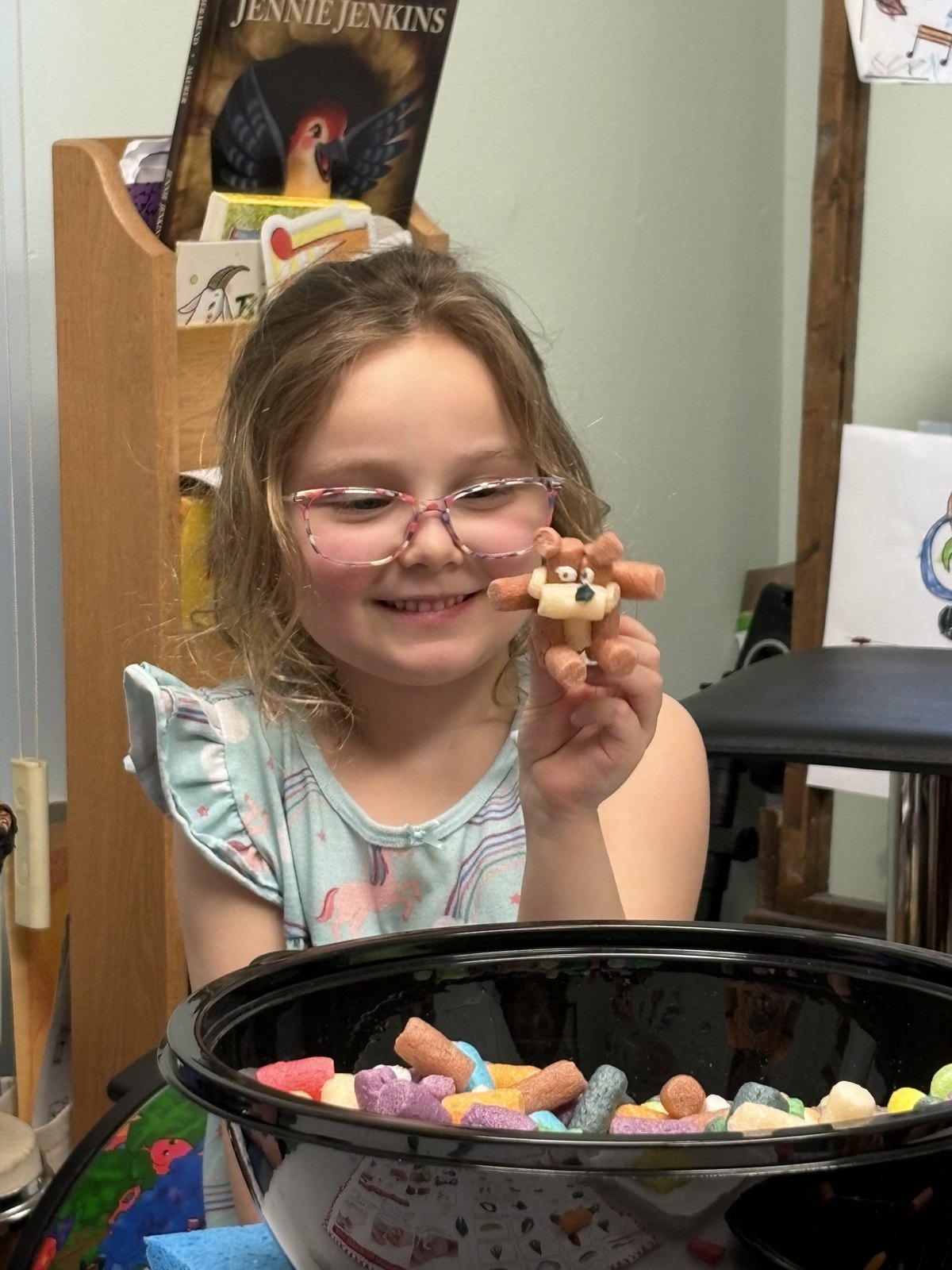 A young arts and crafts student proudly showing a teddy bear she made from dyed sponges
