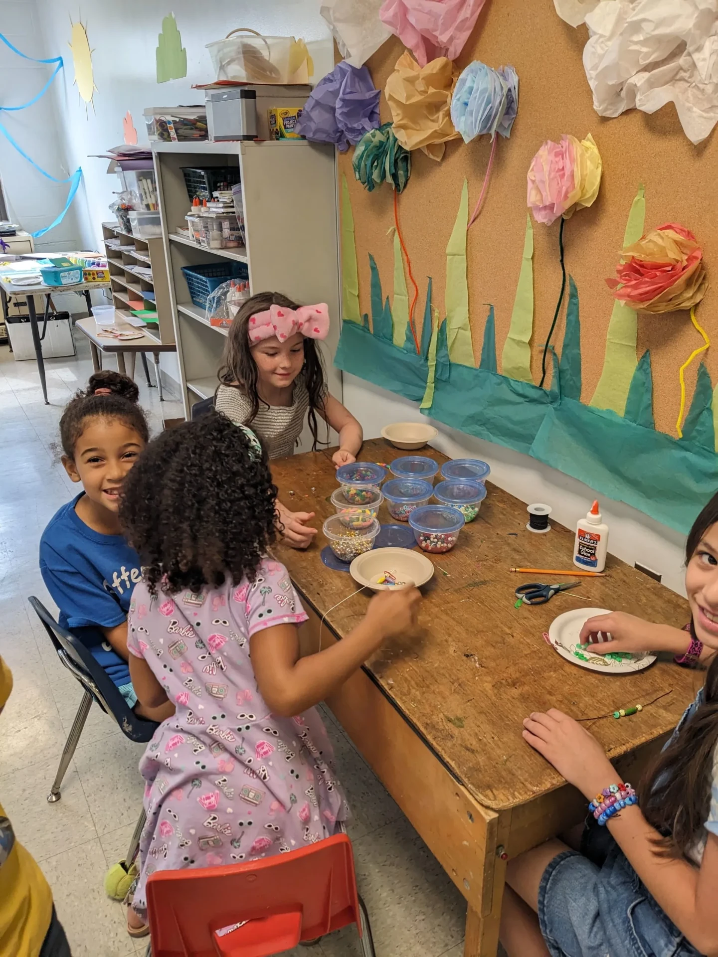 Children stringing beads at a craft table in the NJWA arts and crafts studio