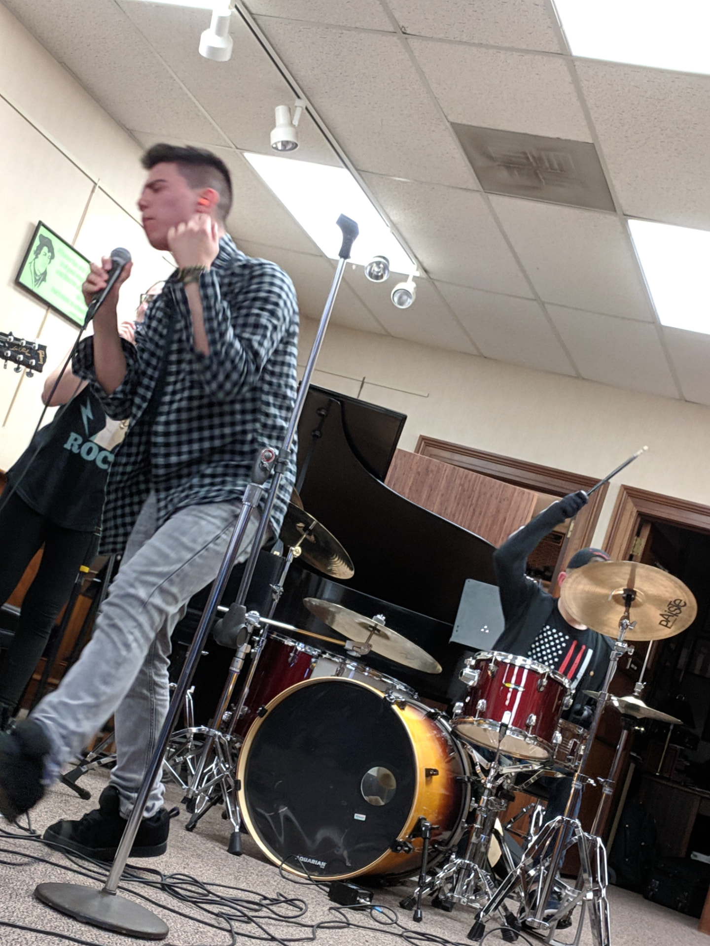 An NJWA student singing while his bandmate plays the drum kit at an in-house rock show