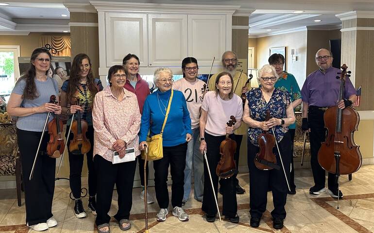 The Wednesday Morning Strings adult string ensemble posing with violins and cello