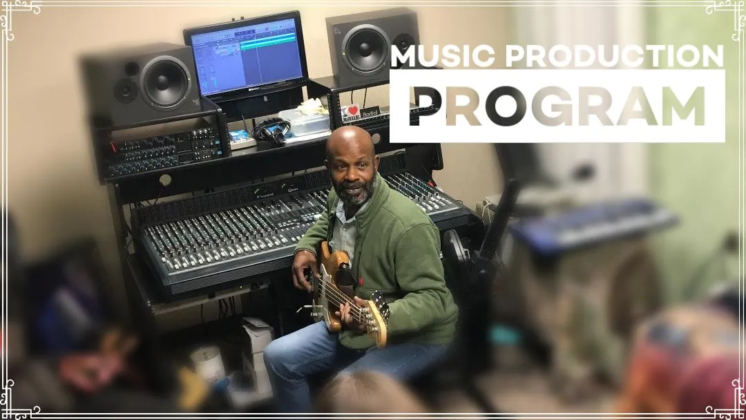 Producer Malcolm Joseph with a bass guitar in the NJWA production studio, in front of the mixing console, studio monitors and a computer running recording software