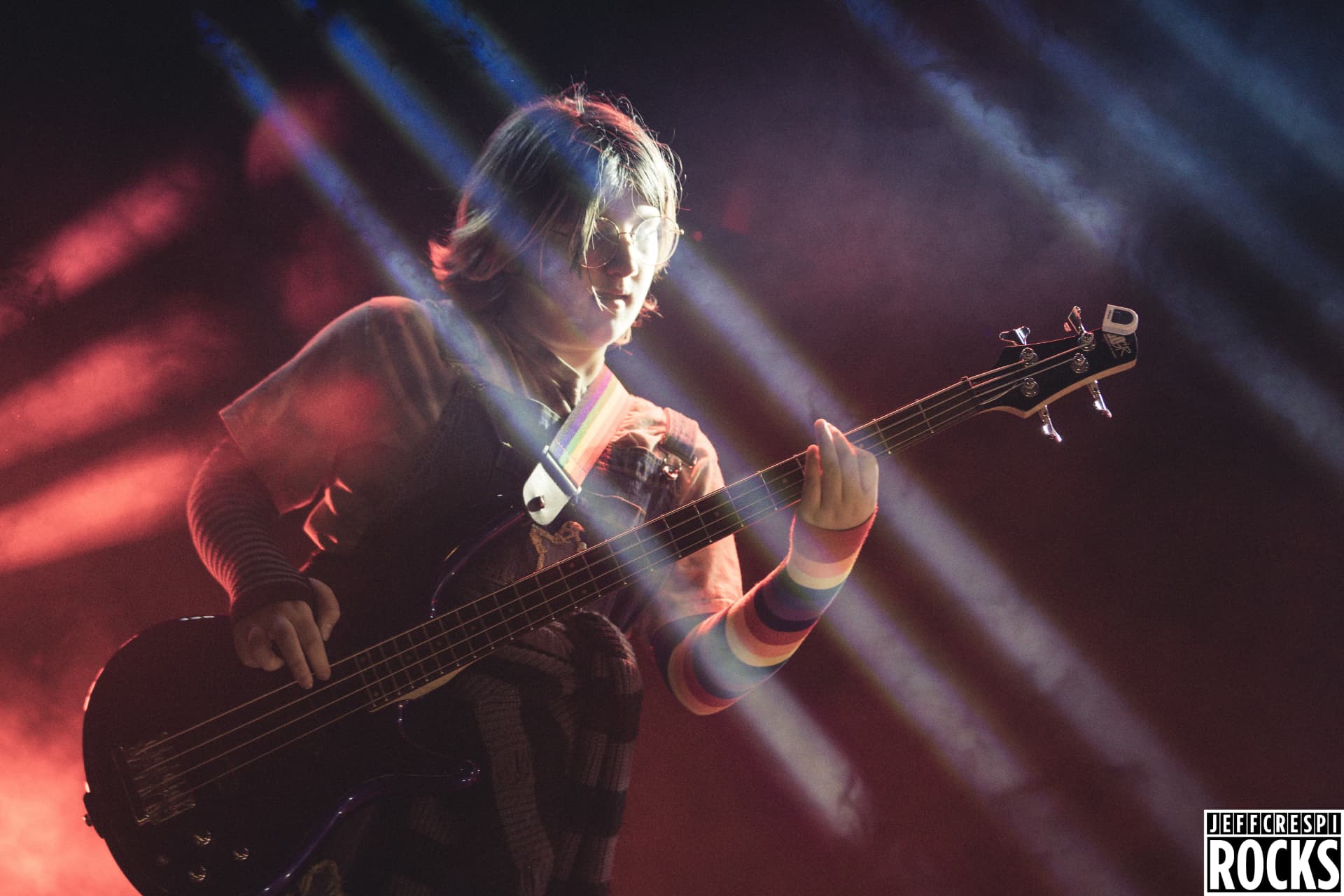 An NJWA student playing bass guitar under colorful stage lights at a rock performance