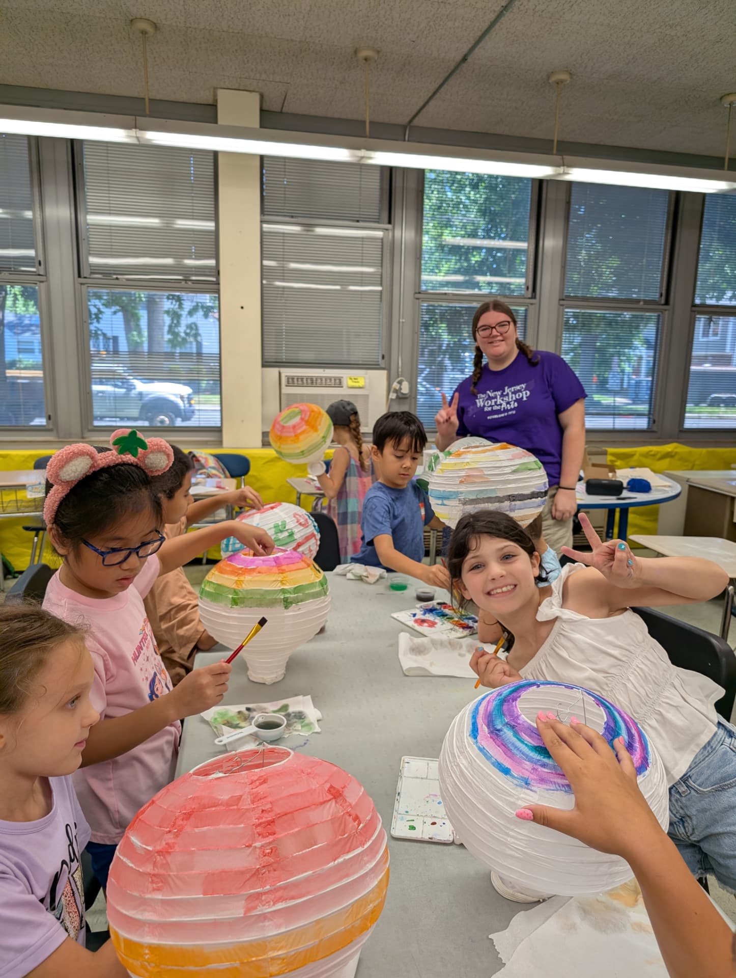 Kids painting colorful paper lanterns in an NJWA summer arts class