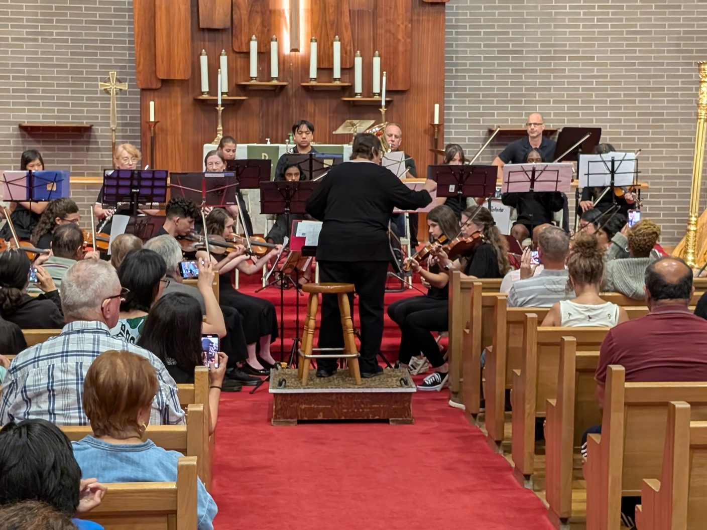 The NJWA orchestra performing with a conductor in a church sanctuary