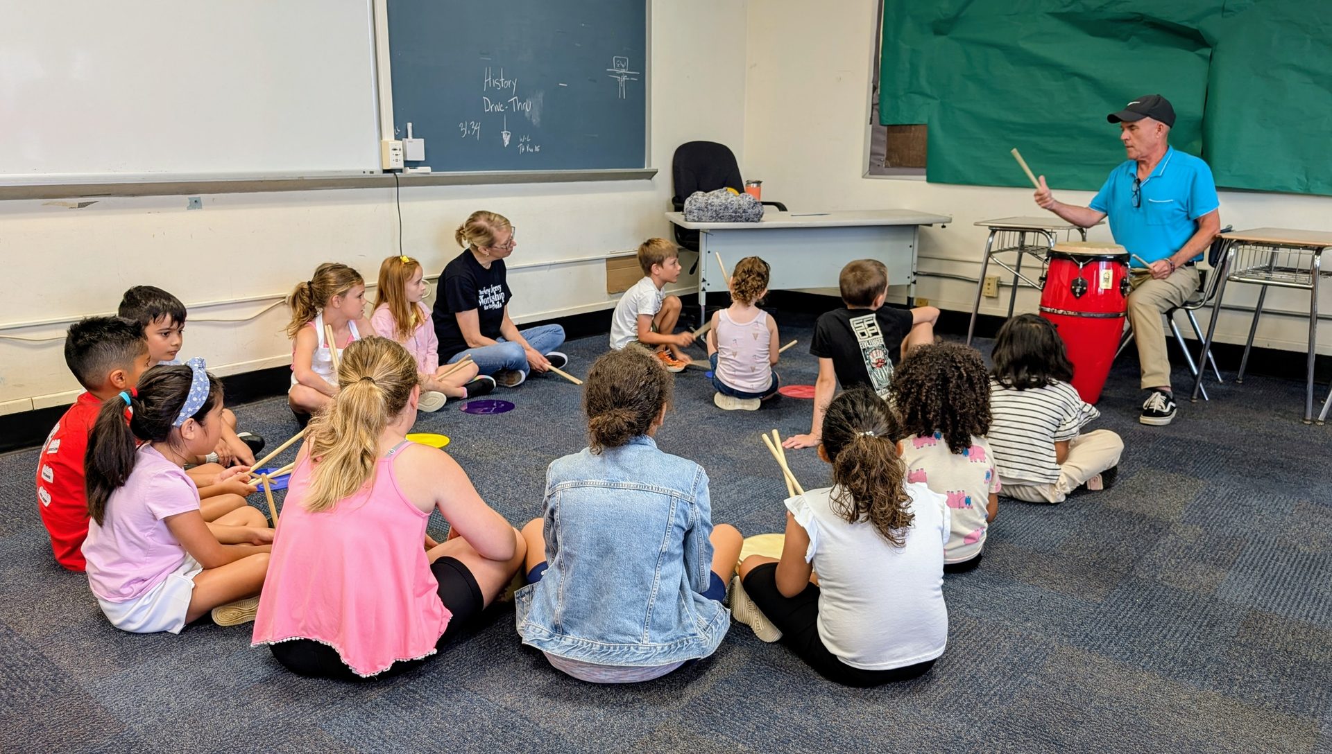 Children sitting in a circle for a music class with their teacher